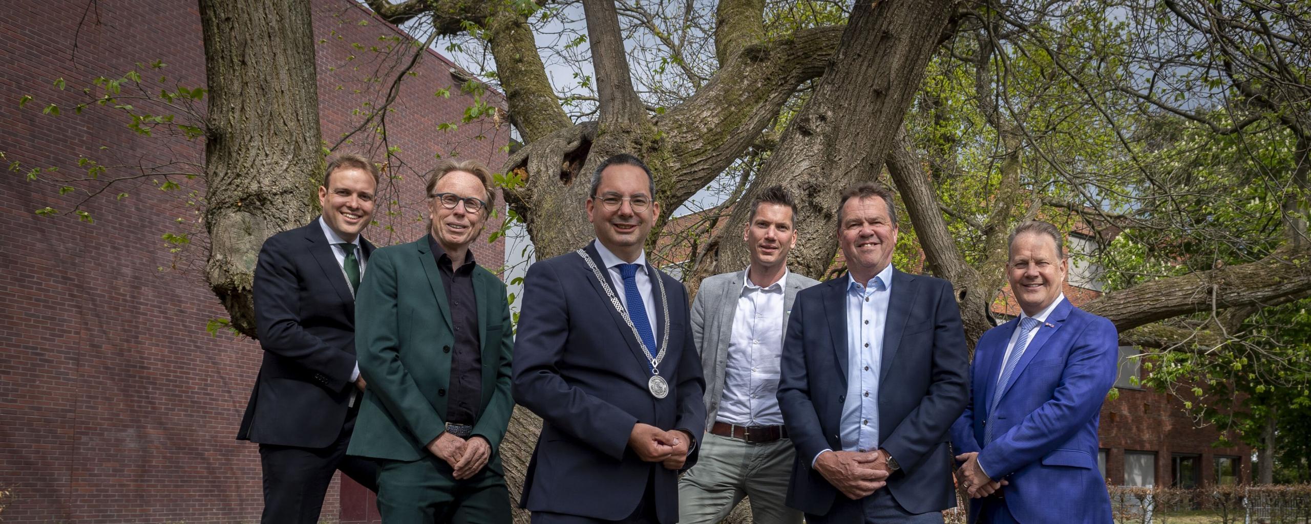 Foto van het college van burgemeester, wethouders en waarnemend gemeentesecretaris. Van links naar rechts: Wethouder de Heer, Wethouder van der Beek, Burgemeester Adriaansen, Wethouder van Agtmaal, Wethouder Schuurbiers, waarnemend gemeentesecretaris Bogers